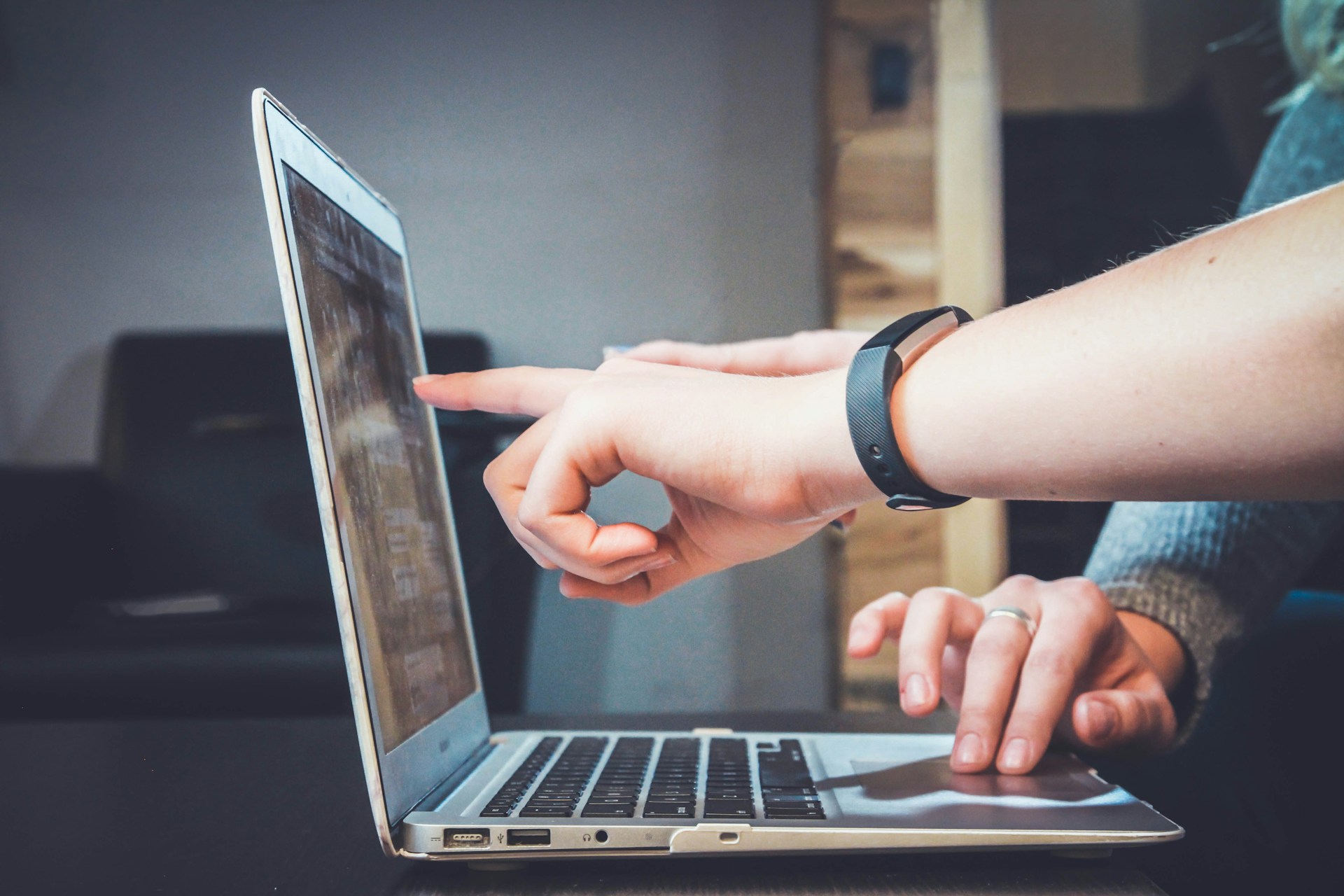 Two professionals analyzing a laptop and pointing fingers at the laptop