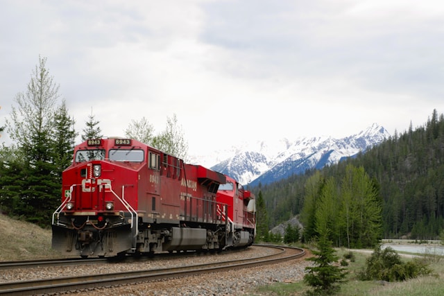 Canadian National train with the rocky mountains in the background surrounded by trees