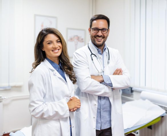 doctors-smiling-into-camera Happy male and ohip female doctors smiling at the camera